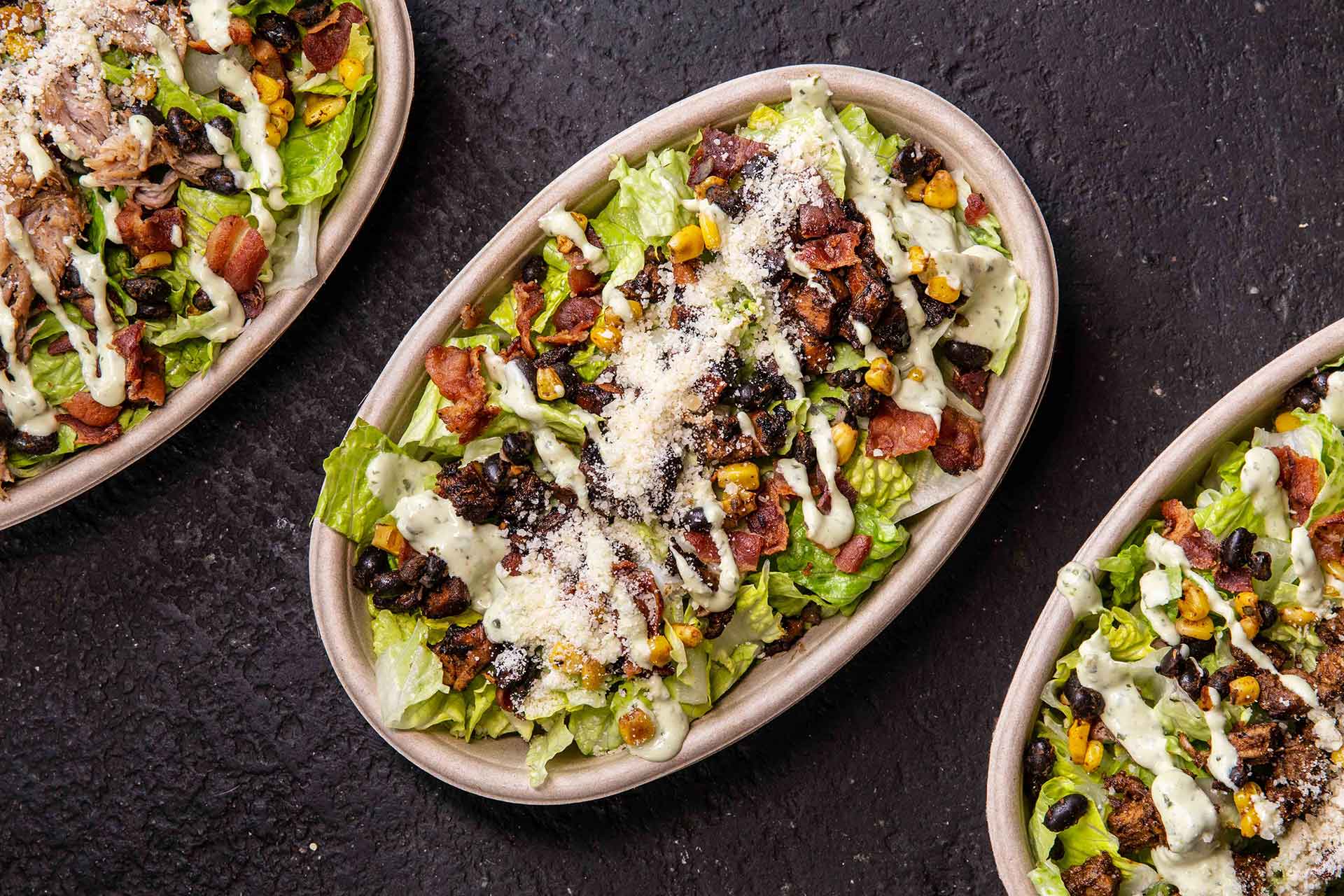 Mexi-Cobb Salad - Bed of Romaine Lettuce, Black Beans, Corn, Pico de Gallo, Crumbled Cotija, Masa Crutons, Avocado Ranch, and Your Choice of Filling.